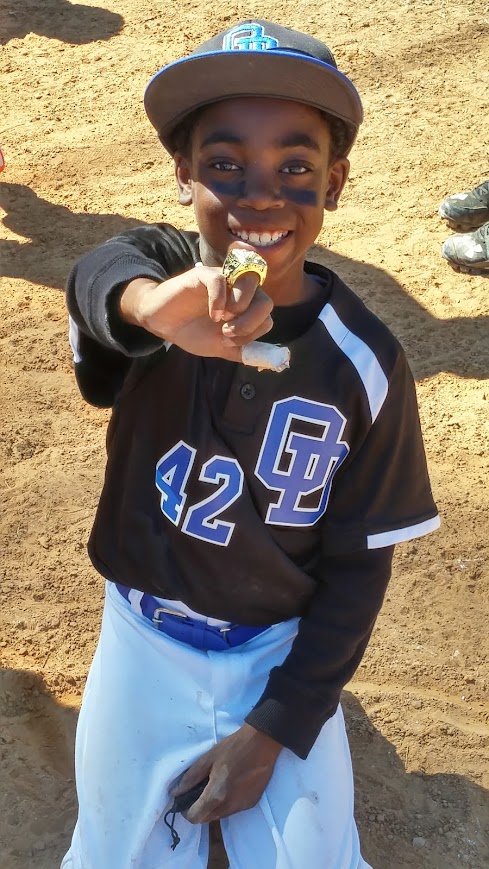 Young Abram poses in his #42 baseball jersey and a championship ring