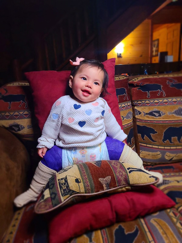 Selena sits on a couch with patterned pillows.