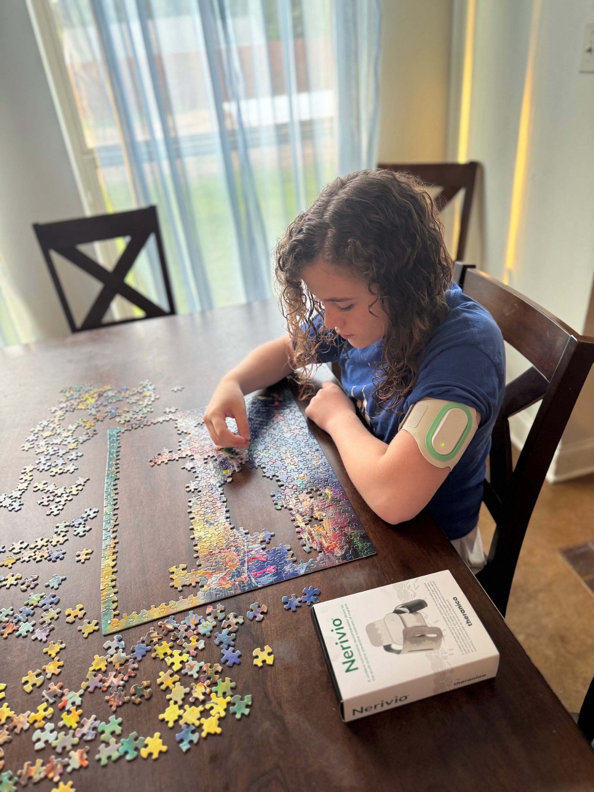 Jaycee works on a puzzle while wearing the Nerivio